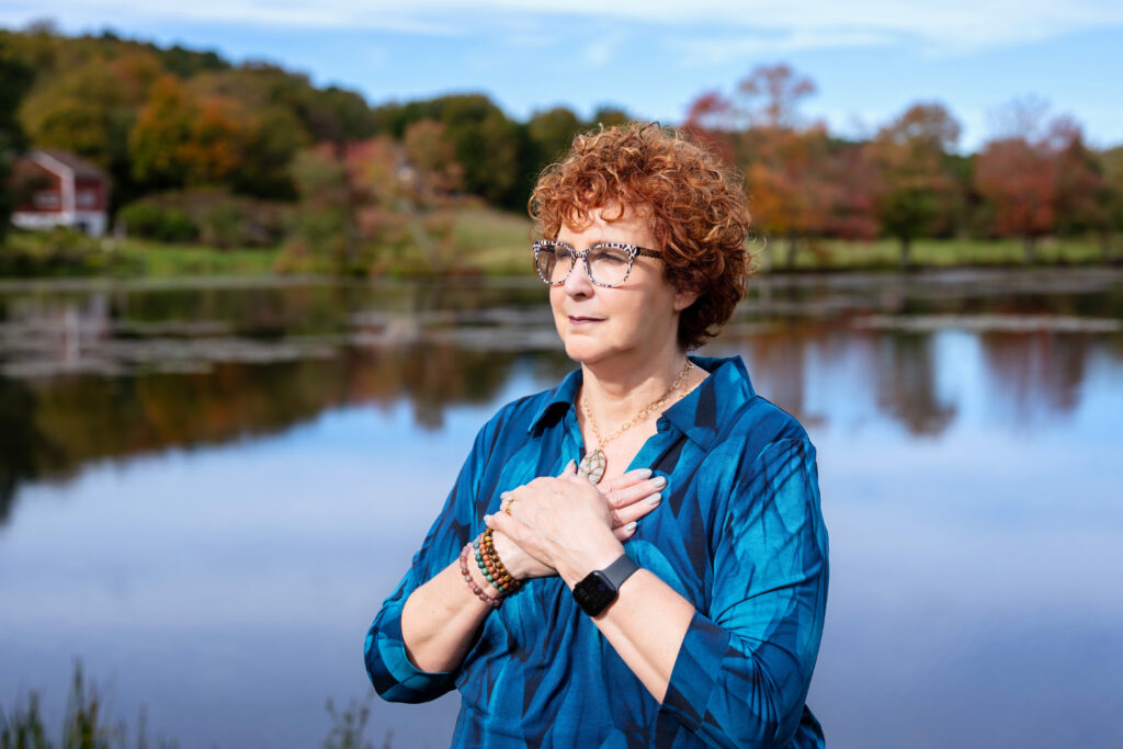 a photo of Allison Field standing with a lake and autumn trees in the background.