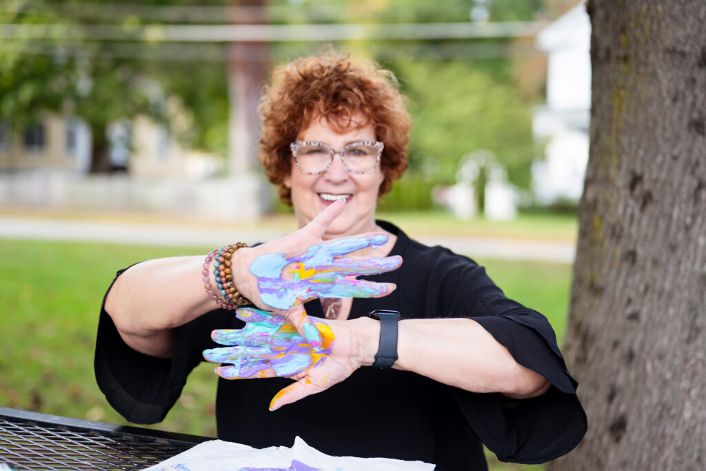 A photo of Allison field with colorful paint on the palms of her hand after an art exercise.