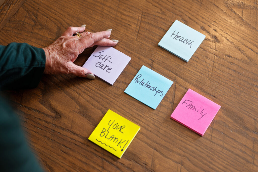 5 pieces of paper on a wooden table that say Health Self Care Relationships Family Your Blank!