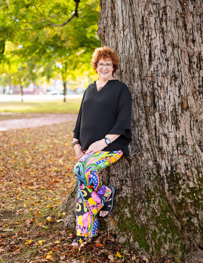 A photo of Allison Field Leaning against a Tree